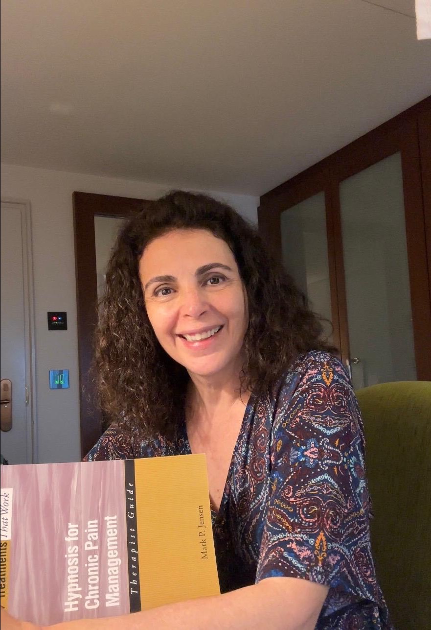 Katia Saul segurando um livro de hipnose clínica